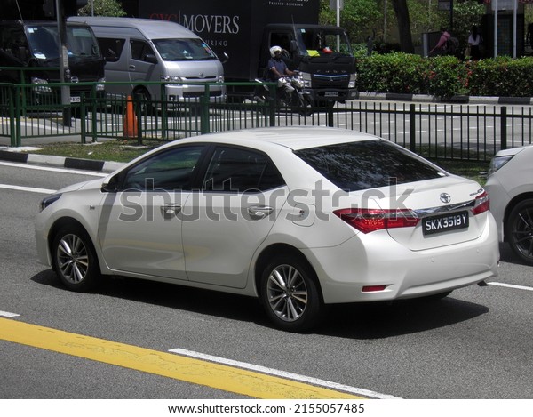 Singapore, february 17 2020: private front-wheel fwd\
drive white pearl metallic color japanese midsize compact sedan\
Toyota Corolla Altis E170 popular cheap car made in Japan on sunny\
highway street 