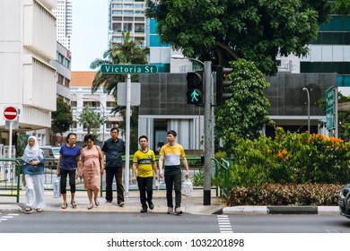 Singapore - February 19, 2018 : Various Group Of Asian People Crossing The Street With Traffic Green Light Sign.