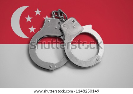 Singapore flag  and police handcuffs. The concept of observance of the law in the country and protection from crime