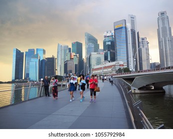 Singapore - January, 2018 : Group Of People Walking On The Bridge At Marina Bay Area, Is A Bay Located In The Central Area Of Finance And Business District Singapore In The Sunset Time.