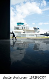 SINGAPORE, SINGAPORE - JANUARY 8, 2021: Silhouette Of An Aircraft Engineer Opening The Hangar Door At Airport