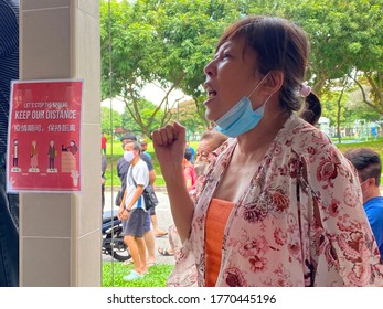 Singapore Jul 05 2020 A Local Auntie Shouting At Coffeeshop During Progress Singapore Party PSP Walkabout, Not Wearing Her Mask. Social Distancing Notice Posted To Her Right. Onlookers In Background.