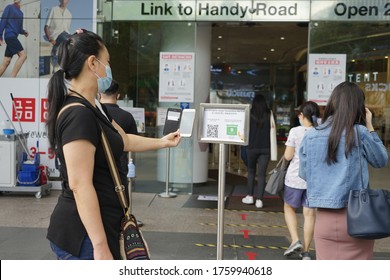 Singapore - June 20, 2020: A Woman Scans A Contact Tracing QR Code Before Entering A Mall On The Second Day Shops Reopen During Phase 2 After Singapore's COVID-19 