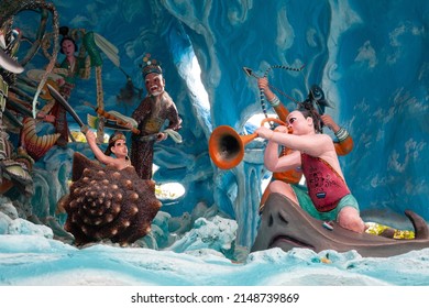 Singapore, Singapore - March 16 2016: Musical Scene Diorama With A Person Blowing A Trumpet On A Sting Ray Amongst Fighting Figures In Water Landscape At Theme Park Haw Par Villa.