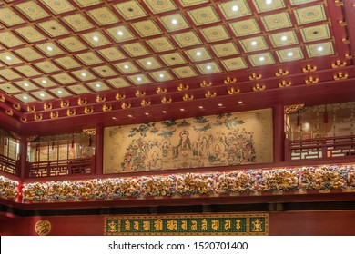 Singapore - March 22, 2019: Buddha Tooth Relic Temple In Chinatown. Preaching Buddha Painting With Disciples On Balcony Wall Above Large Prayer Room. Gold And Maroon Dominant.