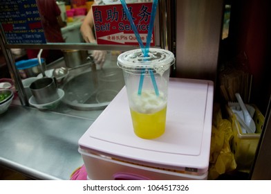 SINGAPORE, SINGAPORE - MARCH 9, 2015: Sugarcane Iced Drink Is Placed On Top Of A Shelf In Singapore Hawker Center. Sugarcane Drink Is A Famous Drink For A Middle Class. There Is A Chef Stands Behind.