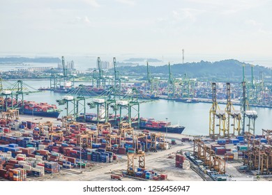 Singapore - November 26, 2018:View of a container terminal at the Port of Singapore. Cargo ships docked in harbor. Ship-to-shore (STS) gantry cranes loading and unloading vessels at shipping yard.