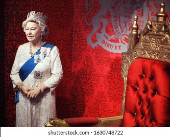 SINGAPORE, OCTOBER 19, 2019: A Beautiful Realistic Waxwork Of Queen Elizabeth II Of The United Kingdom With Crown Standing Near Red Vintage Chair On Display At Madame Tussauds Wax Museum Singapore. 