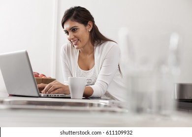 Singapore, Young woman using laptop in kitchen