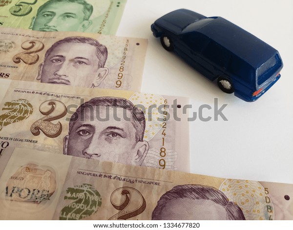 singaporean\
banknotes and figure of a car in dark\
blue