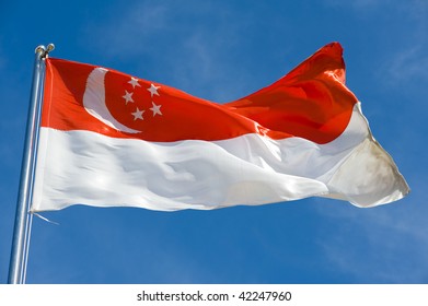 Singaporean Flag On A Pole Against Blue Sky