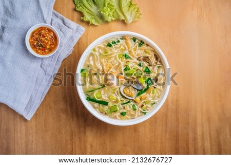 singaporean food Xinghua Lor Mee in a dish with chili sauce, and king's salad leaf top view on wooden background
