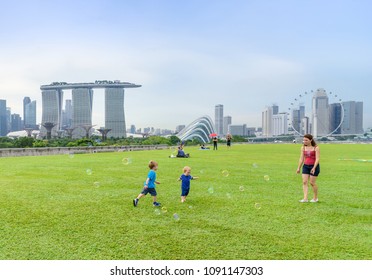SINGAPORE-APRIL 30, 2018: Healthy Family Funny Exercise In Singapore Park Sunset Time At Marina Bay Sand Park, The Most Famous Tourist Attraction In Singapore City, Singapore.