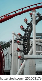 At Singapore's Universal Studios, a roller coaster twists through a loop, with riders in bright red seats enjoying the thrilling turn against a backdrop of the park's architecture.