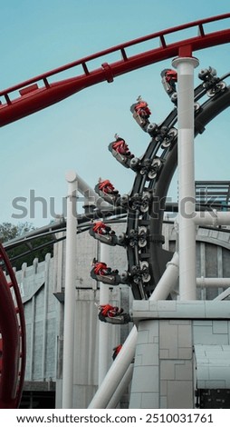 At Singapore's Universal Studios, a roller coaster twists through a loop, with riders in bright red seats enjoying the thrilling turn against a backdrop of the park's architecture.