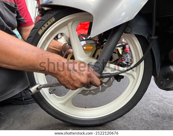 Singapore,singapore - February 12,2022 : A\
dirty hand poreman was repair a tyre at\
workshop.