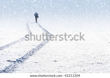 Singe person silhouette through snow and car trails on snow.