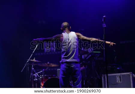 Singer is dancing on stage in front of drums and opening his hands.