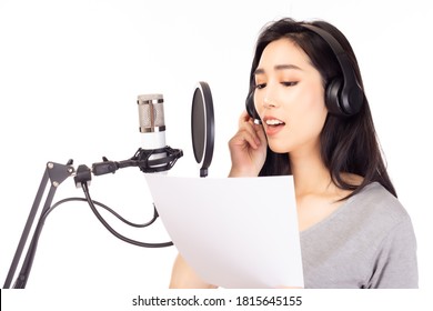 Singer female singing song by reading note on paper in recording studio, using microphone, pop filter for recording music. Singer woman performing and singing in music studio isolated white background - Powered by Shutterstock