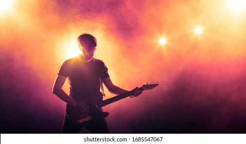 Singer With A Guitar On The Stage In Stage Lighting