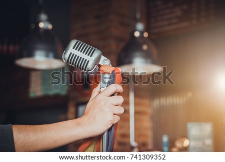 Singer hands holding microphone on stage,Pub,Bar,Restaurant.
