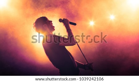Singer holding a microphone stand and performing on stage