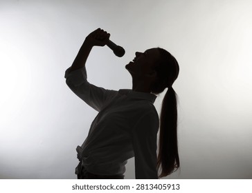 Singer with microphone performing on light grey background