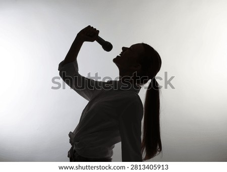 Singer with microphone performing on light grey background