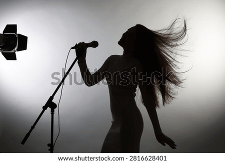 Singer with microphone performing on light grey background