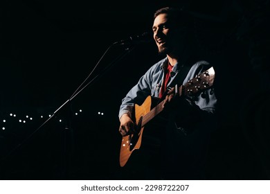 The singer plays an acoustic guitar and sings at a concert - Powered by Shutterstock