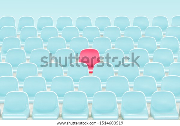 SInger red seat in the middle of light blue chair in\
stadium .