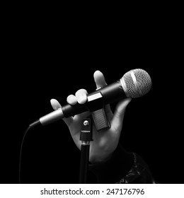 singer right hand holding dynamic microphone, bw filter & isolated on black ( hand sign mean love ) concept = love to sing