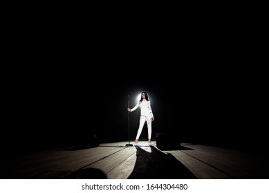 Singer Woman On Stage With Black Background In A Beam Of White Light