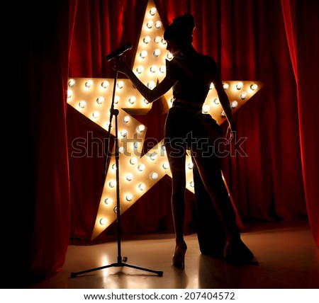 Singer woman on stage with broadway star on background