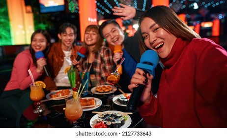 Singing into microphone and making selfie at karaoke party in club, Young people cheering and laughing together, Drinking cocktails at party, Enjoying friendship together in bar, - Powered by Shutterstock