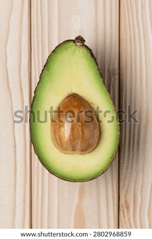 Single avocado half on light wooden background top view