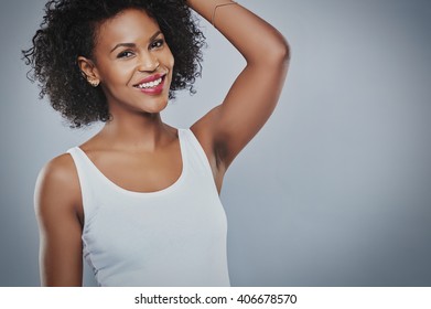 Single Beautiful Smiling African-American Woman Wearing Sleeveless White Undershirt With Hand Up Toward Head Over Gray Copy Space