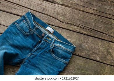 Single blue denim jean, trouser on wooden rustic background, fashion design 