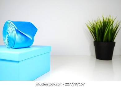 single blue neck tie rolled up isolated on blue box with plain white background selective focus blur background, male fashion neck tie isolated close up shot single object   - Shutterstock ID 2277797157