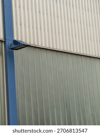 Single blue security light is mounted on the exterior wall of a modern industrial building, casting light onto the corrugated metal and translucent panels