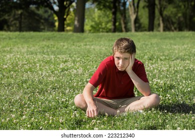 Single Bored Teen Boy Sitting On Grass