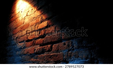 A single, bright spotlight casts a warm glow on a rough, weathered brick wall, creating a stark contrast with the surrounding deep shadows.