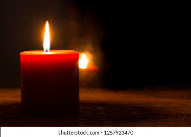 Single burning red candle and flame reflection in the dark window. Concept of Christmas Season, memory, condolence, hope - Powered by Shutterstock