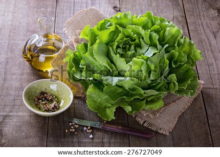 Single butter lettuce head, oil and seasoning over rustic wooden background