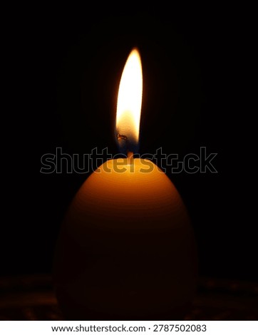 Single candle burning in the dark