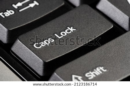 Single caps lock key on a simple black desktop PC computer keyboard, object detail, extreme closeup. Using capital letters, typing in all caps, screaming, shouting, emphasis abstract concept, nobody Imagine de stoc © 
