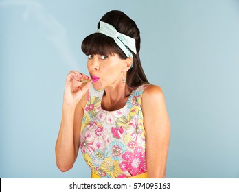 Single Caucasian woman in sleeveless dress puffing on a marijuana cigarette