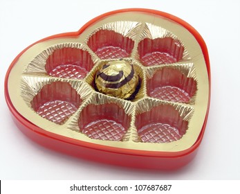 A Single Chocolate In Empty Heart Shaped Box On Isolated White Background.