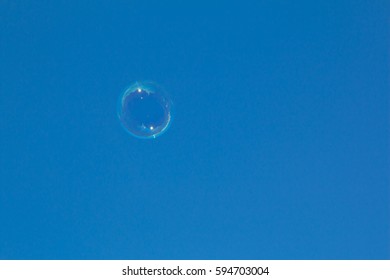Single Clear Soap Bubble Float against Deep Blue Sky Background. This shows Possible Ideas for Imagination, Dream, Clean Atmosphere, Fresh air and Green environment.
