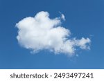 Single cumulus cloud with blue sky background